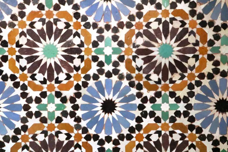 A close view of interlaced zellige stars in blue, ochre, brown and white with turquoise centres.